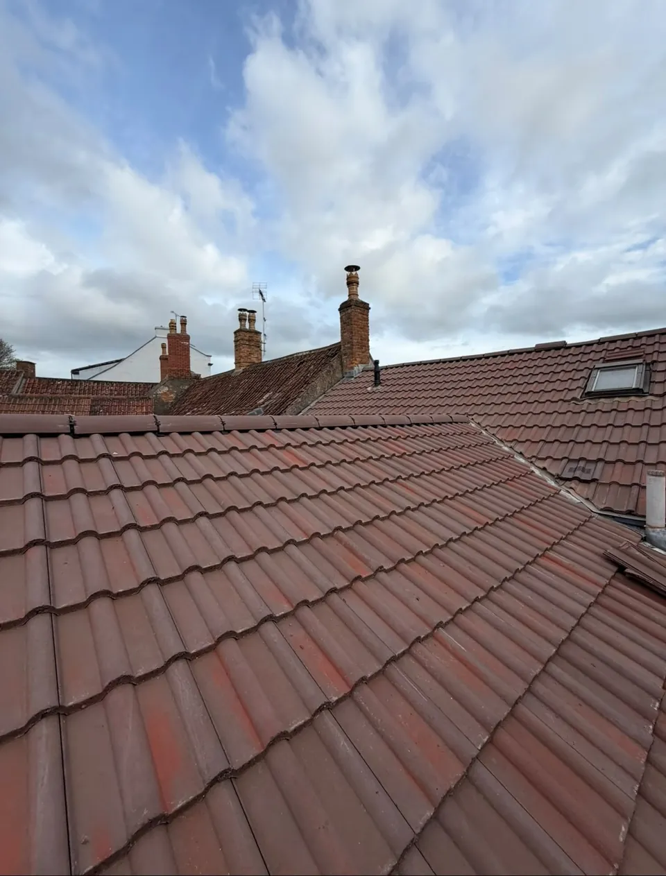 New red tiled roof among neighbouring chimneys